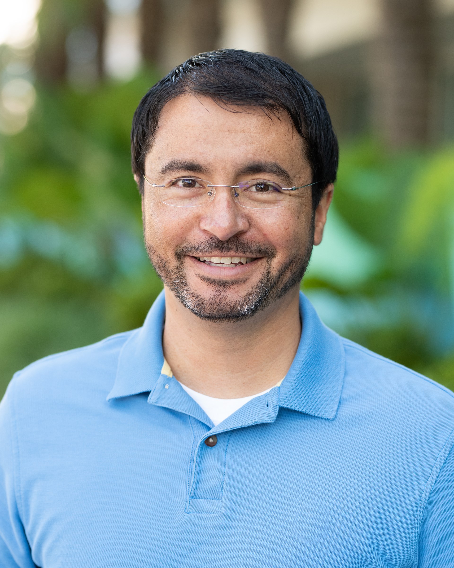 Man in blue shirt with glasses smiling