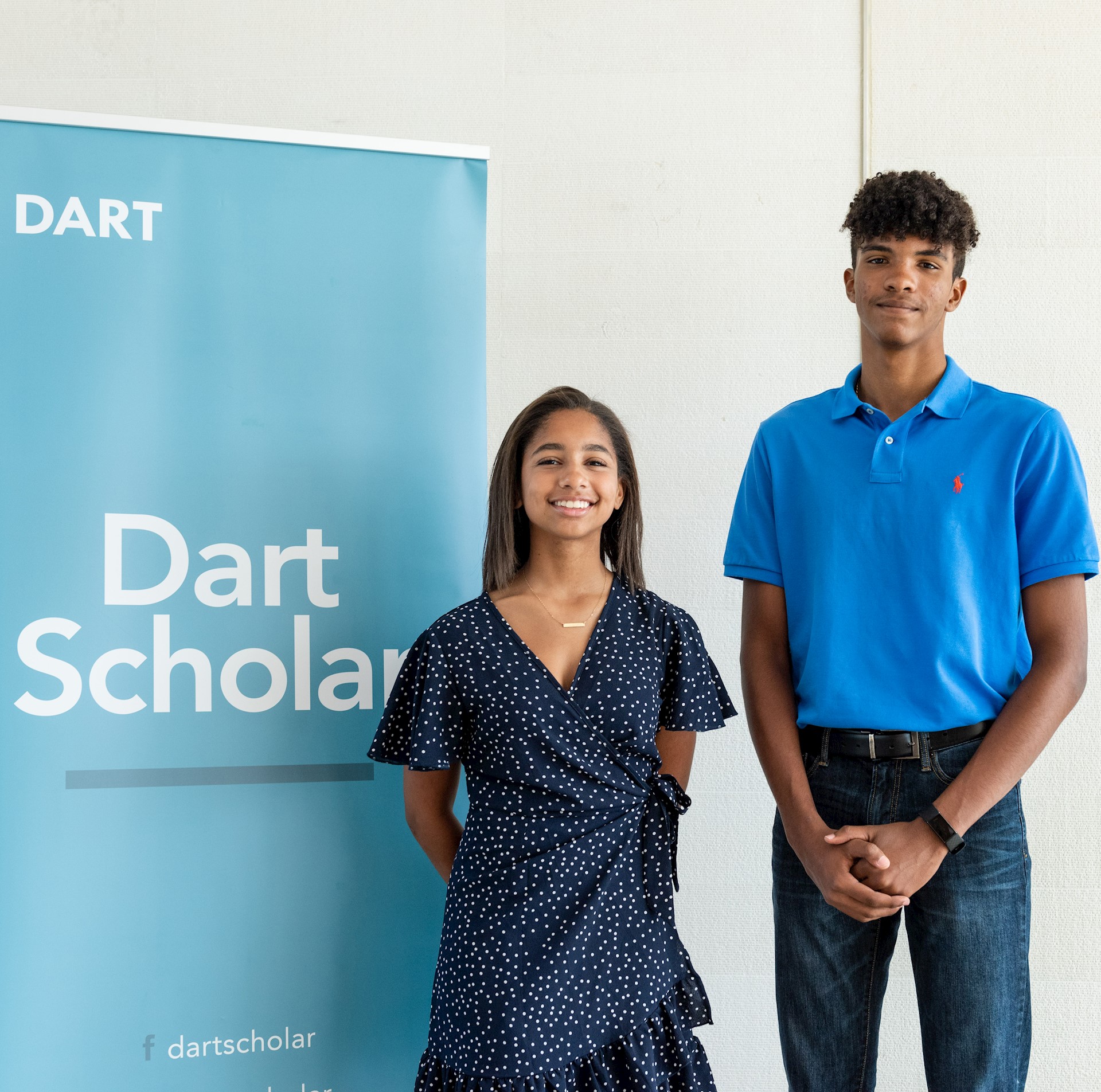 young man and woman in front of banner 