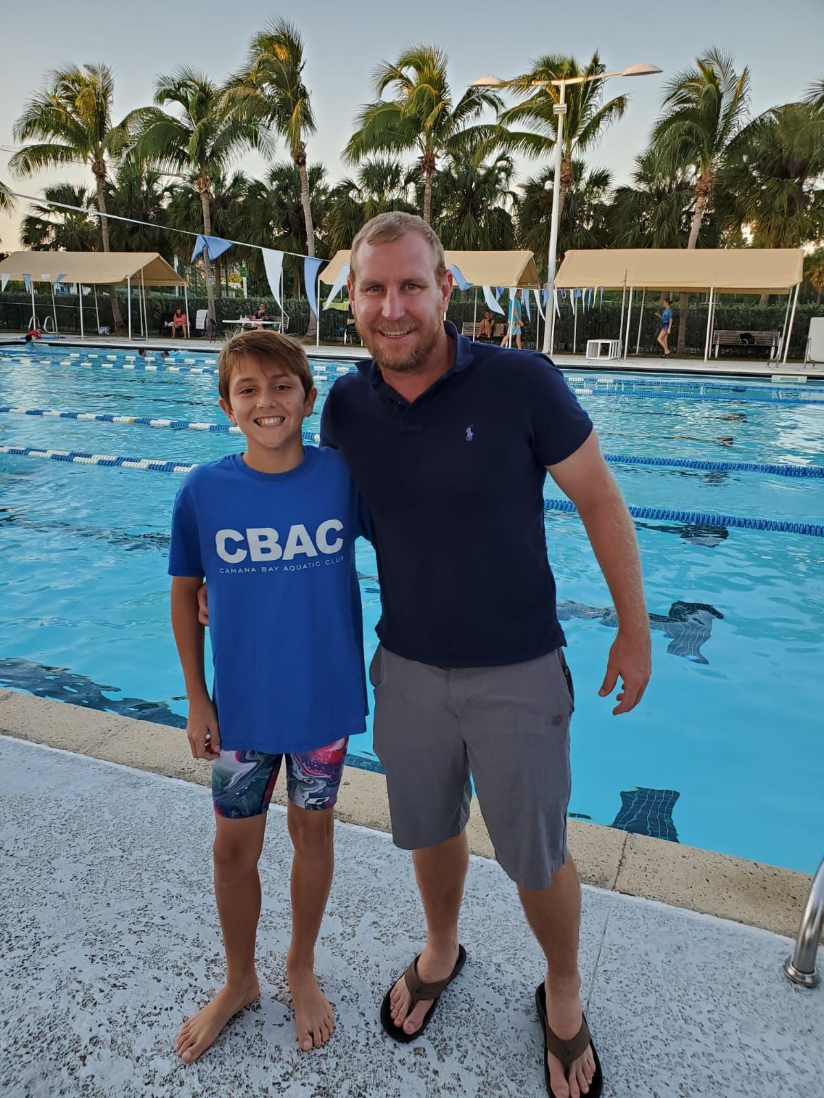 young male swimmer and man by pool