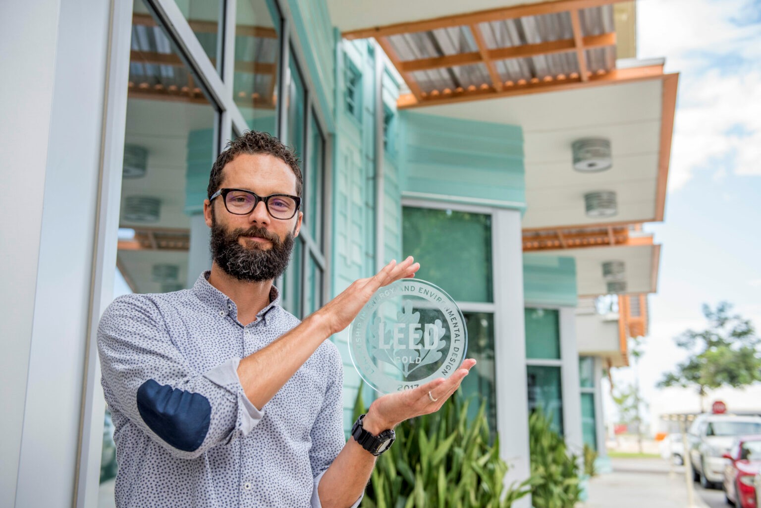 White man holds LEED glass plaque award