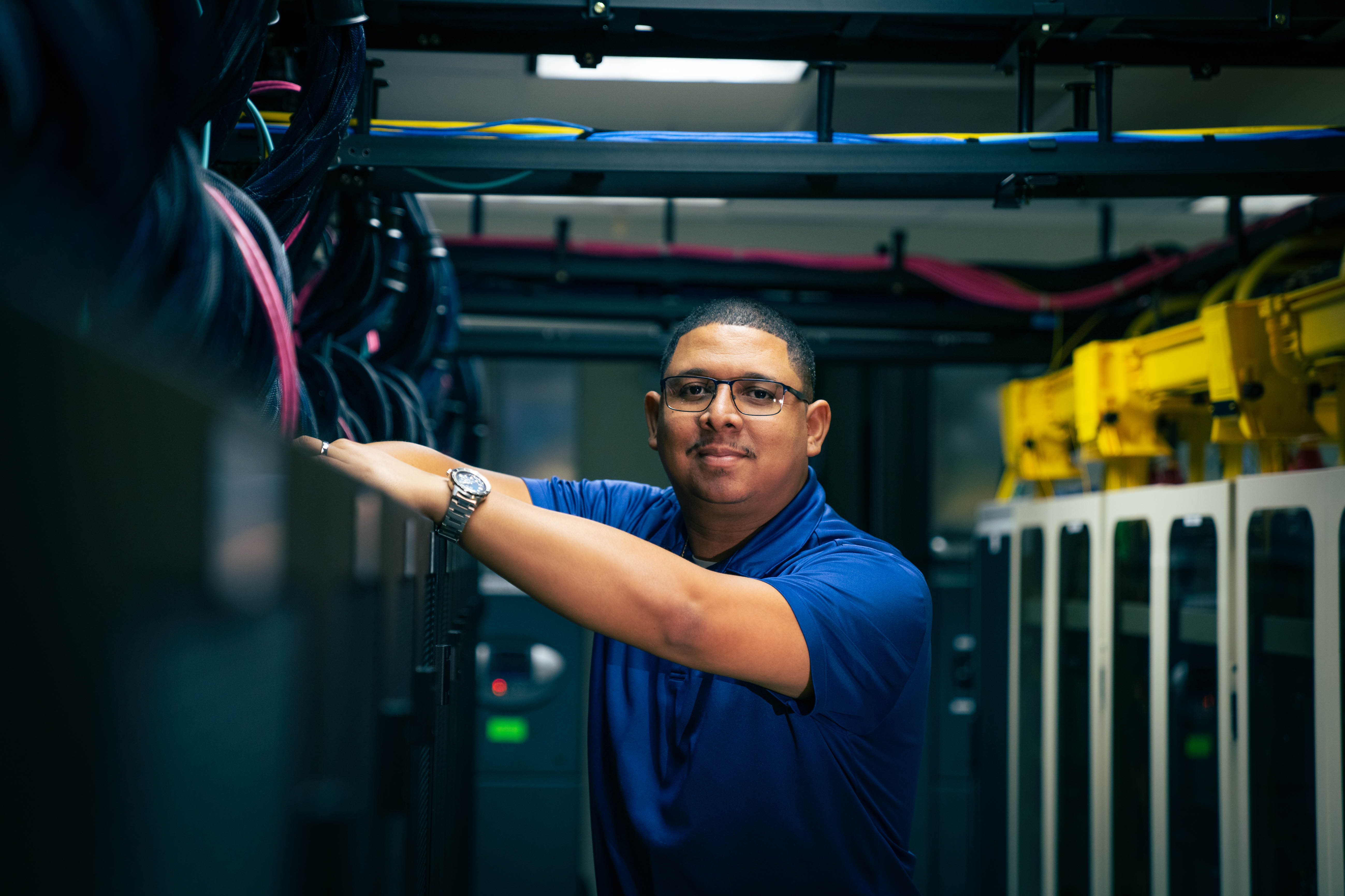 Man in data systems room poses for camera