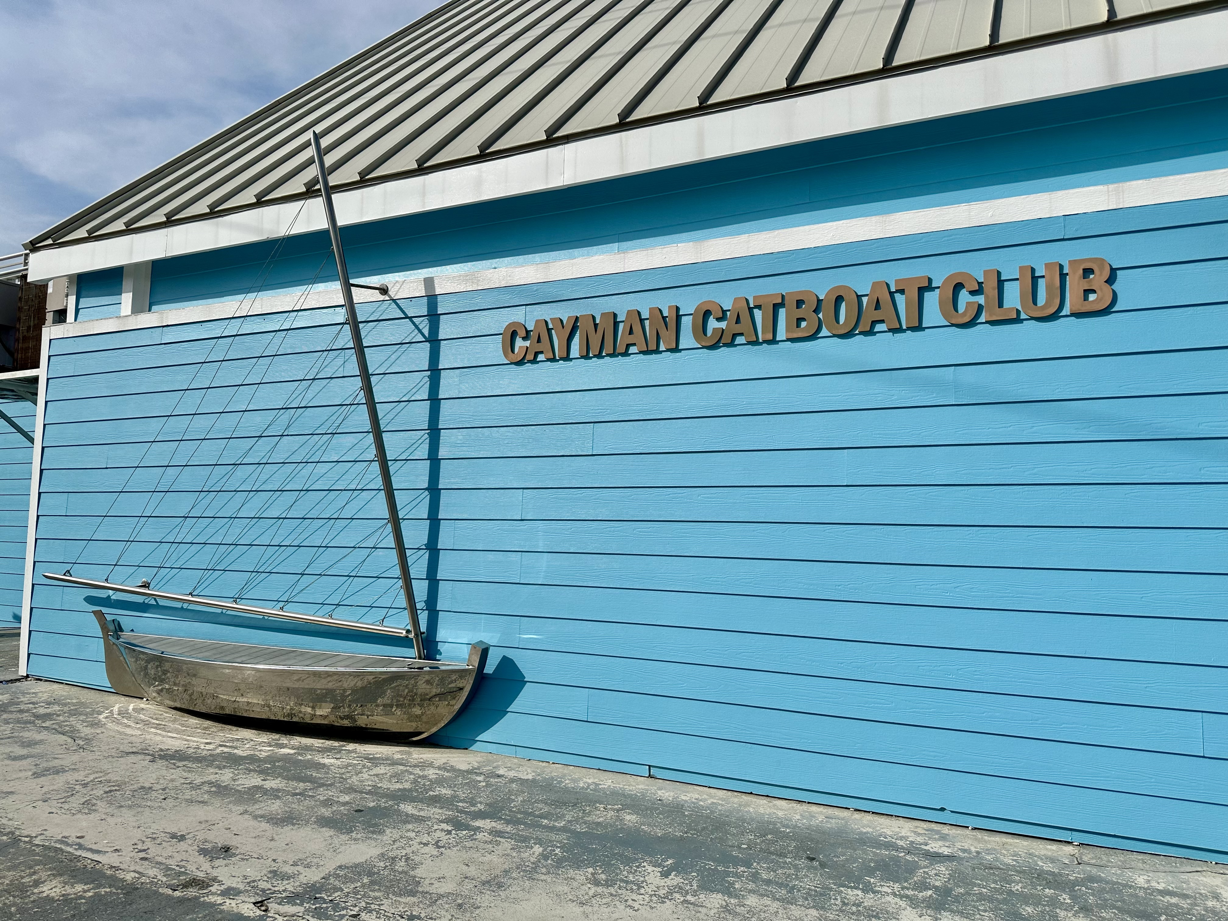 metal catboat sculpture sits on blue wall of Cayman Catboat Club