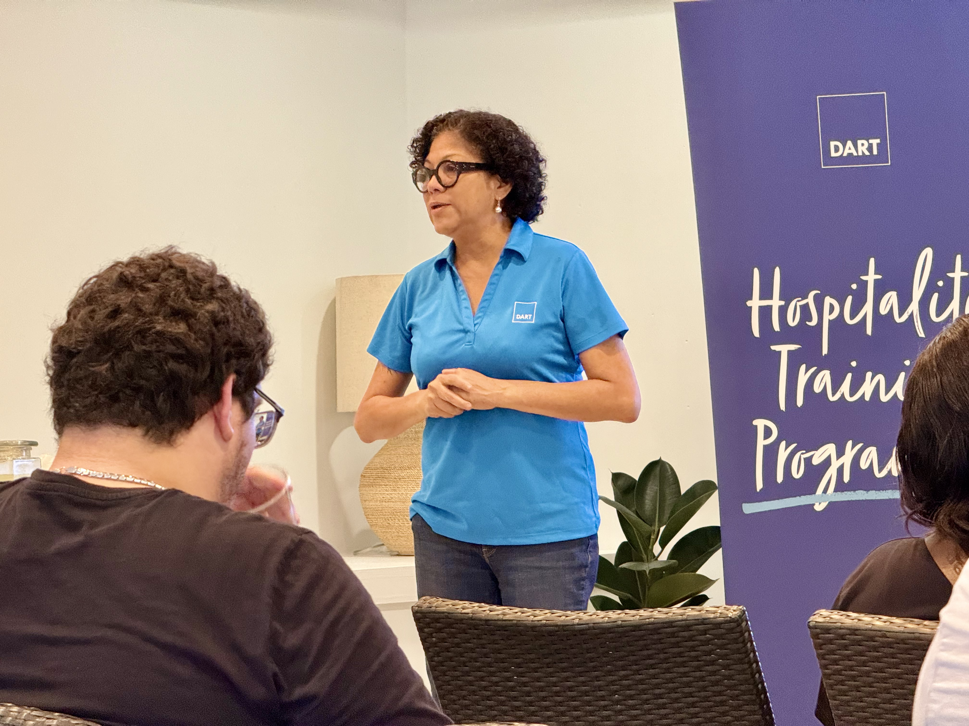 Woman in blue shirt talking to a room of people